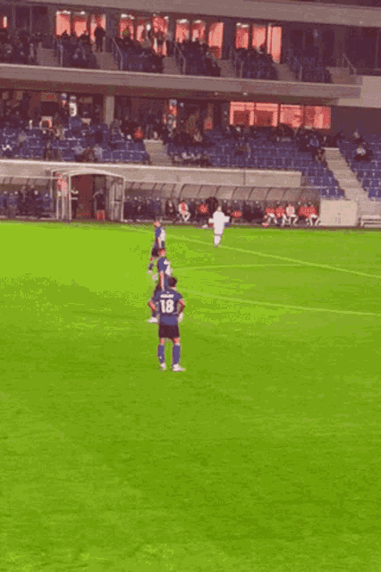 a soccer player with the number 18 on his jersey stands on the field