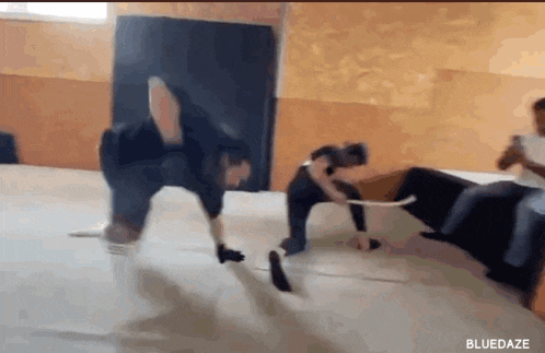 a man is doing a handstand on a mat in a gym while another man watches .