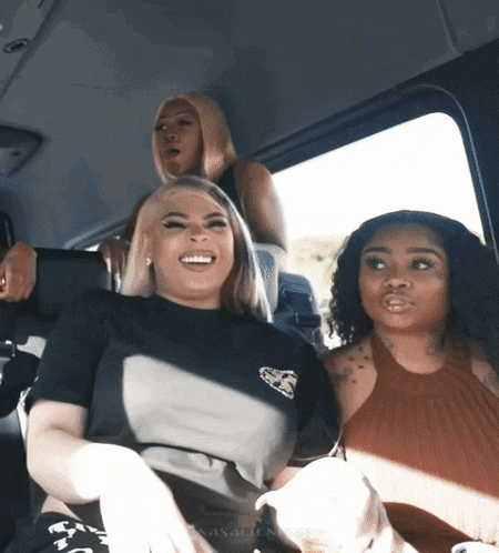three women are sitting in a car and one of them is wearing a t-shirt that says ' snoop dogg '