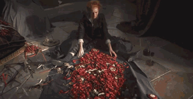 a woman with red hair is laying on a pile of red ribbons