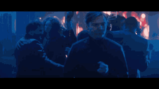 a man stands in a crowd of people in a dark room
