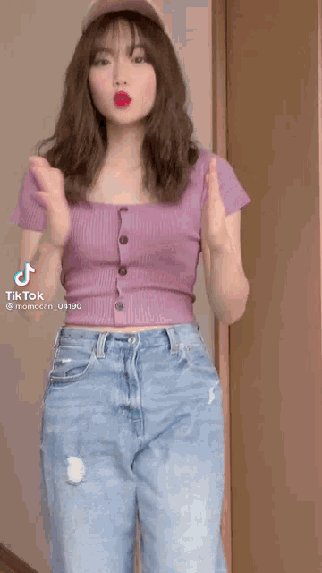 a woman in a purple crop top and blue jeans is dancing