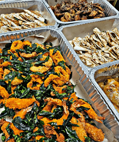 several trays of food including fried shrimp and chicken