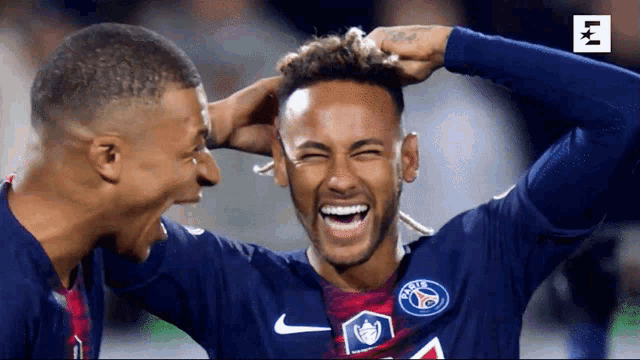 two soccer players are laughing and one has a nike logo on his jersey
