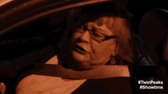 a woman wearing glasses is sitting in a car with #twinpeaks showtime written on the bottom
