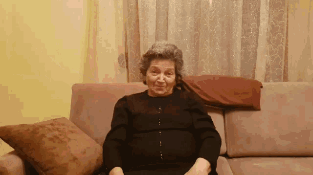 an elderly woman is sitting on a couch with a pillow