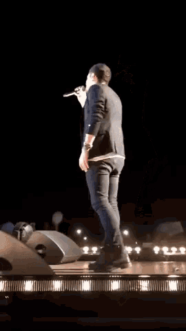 a man in a suit is singing into a microphone on a stage at night