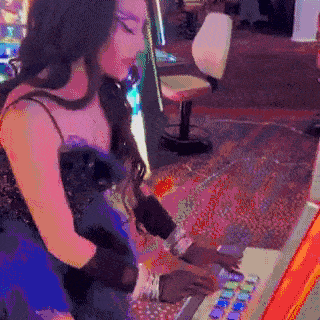 a woman is playing a slot machine in a casino
