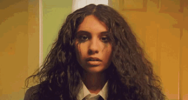 a woman with curly hair and a white shirt and tie