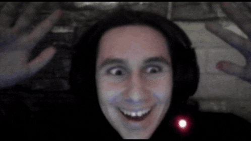 a man wearing headphones is smiling with his hands outstretched in front of his face