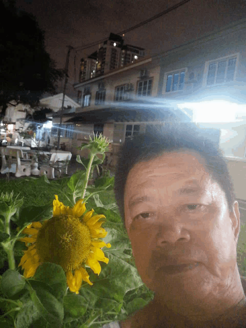 a man is taking a selfie with a sunflower in the foreground