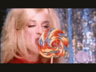 a woman is eating a colorful lollipop in a video