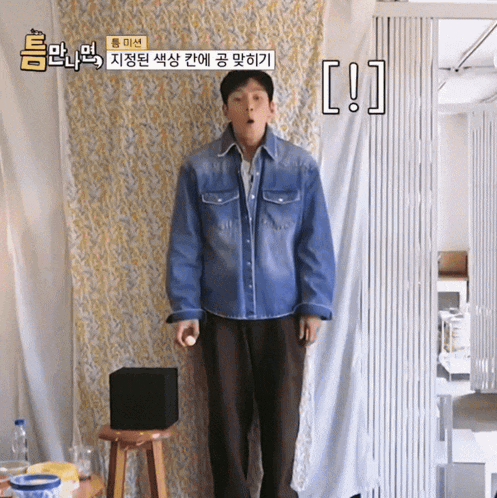 a man in a denim shirt is standing in front of a white curtain with chinese writing on it