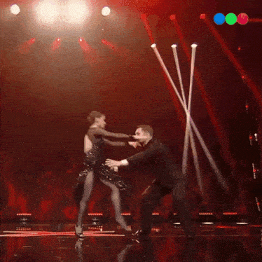 a man and a woman are dancing on a stage with a red background