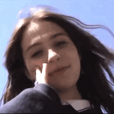 a close up of a woman 's face with her finger on her nose .