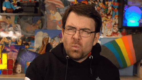 a man wearing glasses and a black hoodie making a face