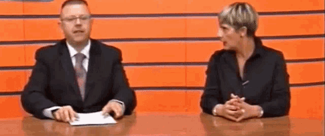a man and a woman are sitting at a table talking to each other .
