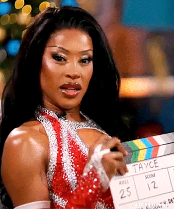 a woman in a red dress is holding a clapper board in her hand .