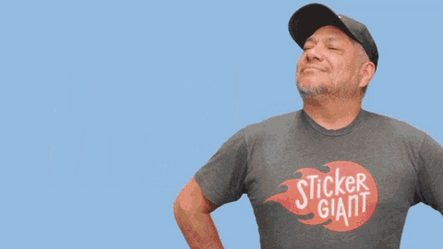 a man wearing a sticker giant t-shirt stands in front of a blue background