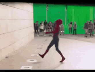 a person in a spiderman costume is walking on a green screen .