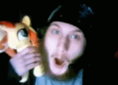 a man in a black hat is holding a stuffed pony in front of his face