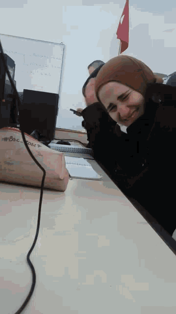 a woman in a hijab is sitting at a desk with a pencil case that says doc on it