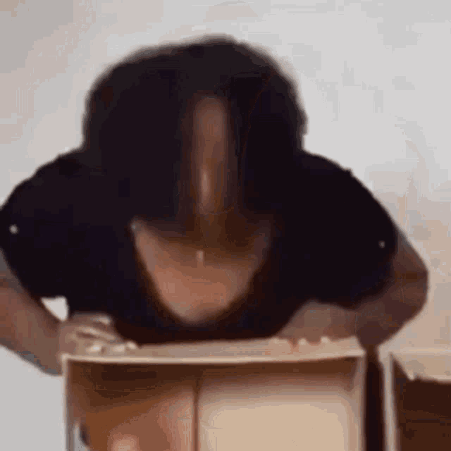 a woman is doing push ups while holding a box in front of her face .