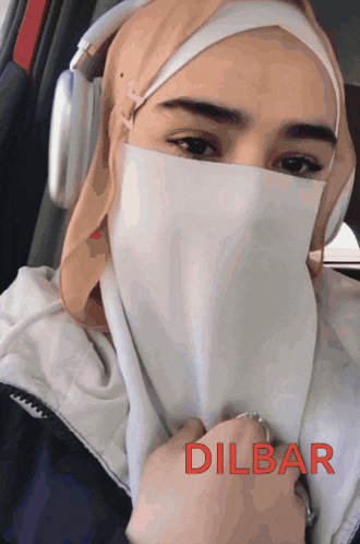 a woman wearing a hijab and headphones has dilbar written on the bottom