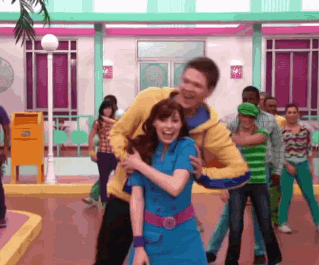 a man in a yellow jacket holds a woman in a blue dress
