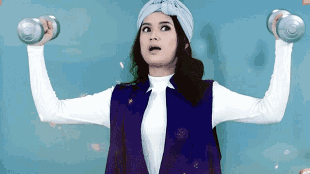 a woman in a turban is lifting dumbbells