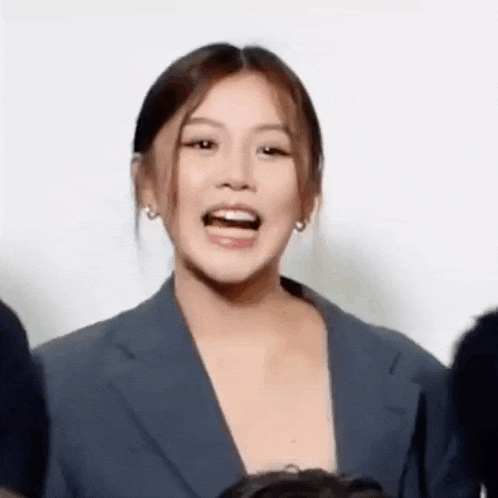 a woman in a suit is making a funny face with her mouth open .