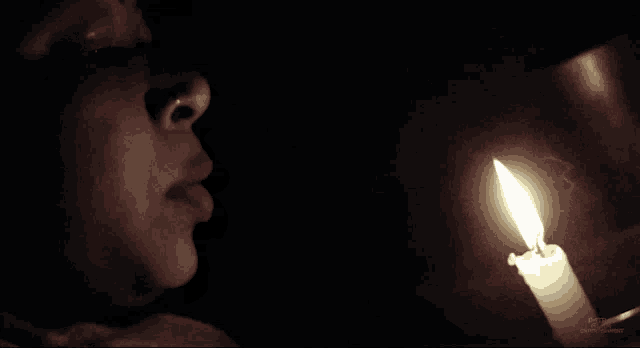 a woman looks at a lit candle in the dark with a watermark that says ' pixabay ' on it