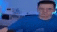 a blurry picture of a man in a blue shirt talking into a microphone .