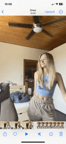 a woman is dancing in a room with a ceiling fan and the time 10:08