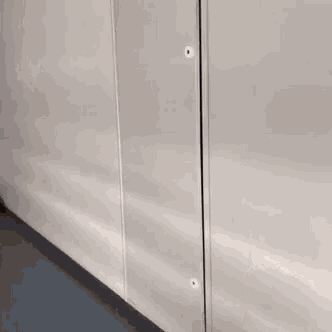 a woman is standing in a doorway with a white wall behind her