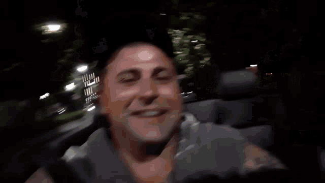 a man with a lot of tattoos is sitting in the back seat of a car at night .