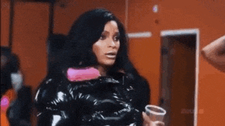 a woman in a black jacket is holding a cup of coffee in a room .
