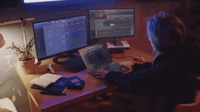 a woman is sitting at a desk with a laptop and two monitors and the words actual footage of me making music above her