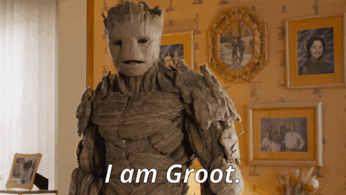 a statue of groot says i am groot in front of pictures on the wall