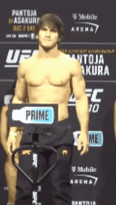 a shirtless man stands in front of a sign that says " prime "