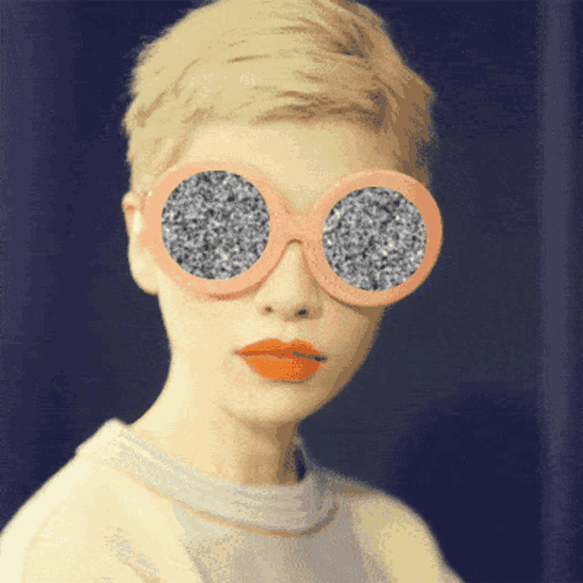 a woman wearing a pair of pink sunglasses with a gray pattern on them