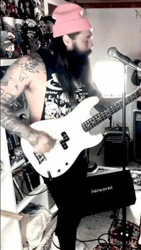 a man in a pink hat is playing a white guitar in front of a microphone that says headrush