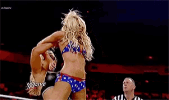 a woman is laying on her back in a wrestling ring while a referee watches on