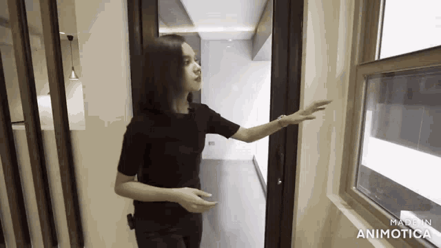 a woman in a black shirt is pointing at a window in a room made by animatica