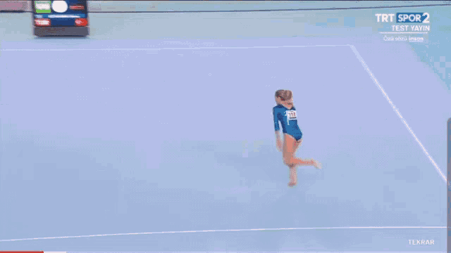 a female gymnast is doing a trick on a trampoline in front of a scoreboard that says turk
