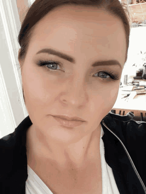 a close up of a woman 's face with a white shirt and a black jacket