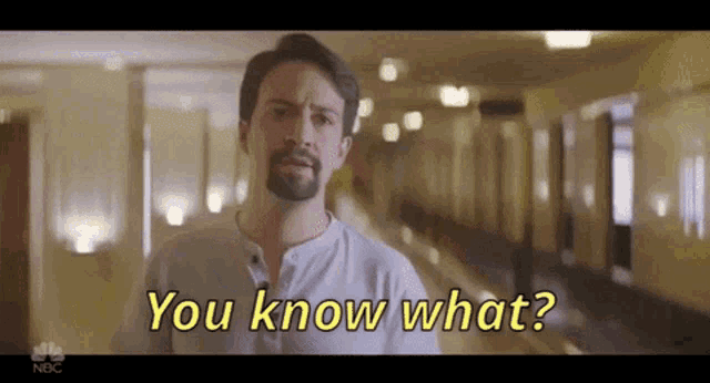 a man with a beard is standing in a hallway and says `` you know what ? ''