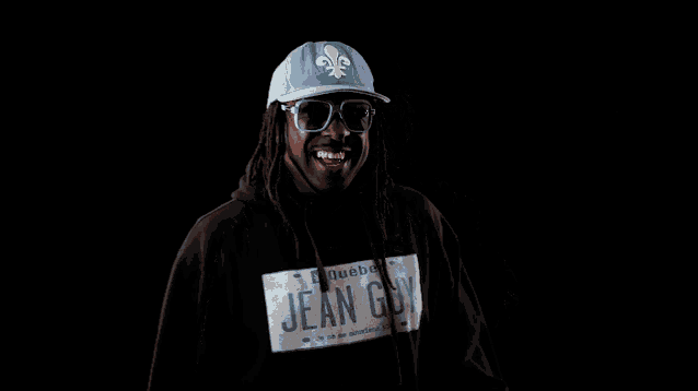 a man wearing a blue hat and glasses has a jean g. sweatshirt on