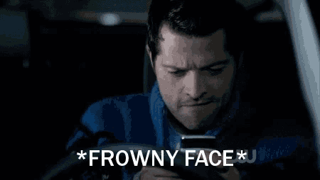 a man sitting in a car looking at a cell phone with the words * frowny face * written above him