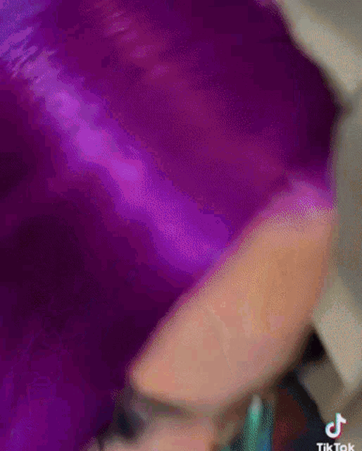 a close up of a woman 's face with purple hair and a purple wig .